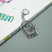 grumpy ghost keychain with book behind it