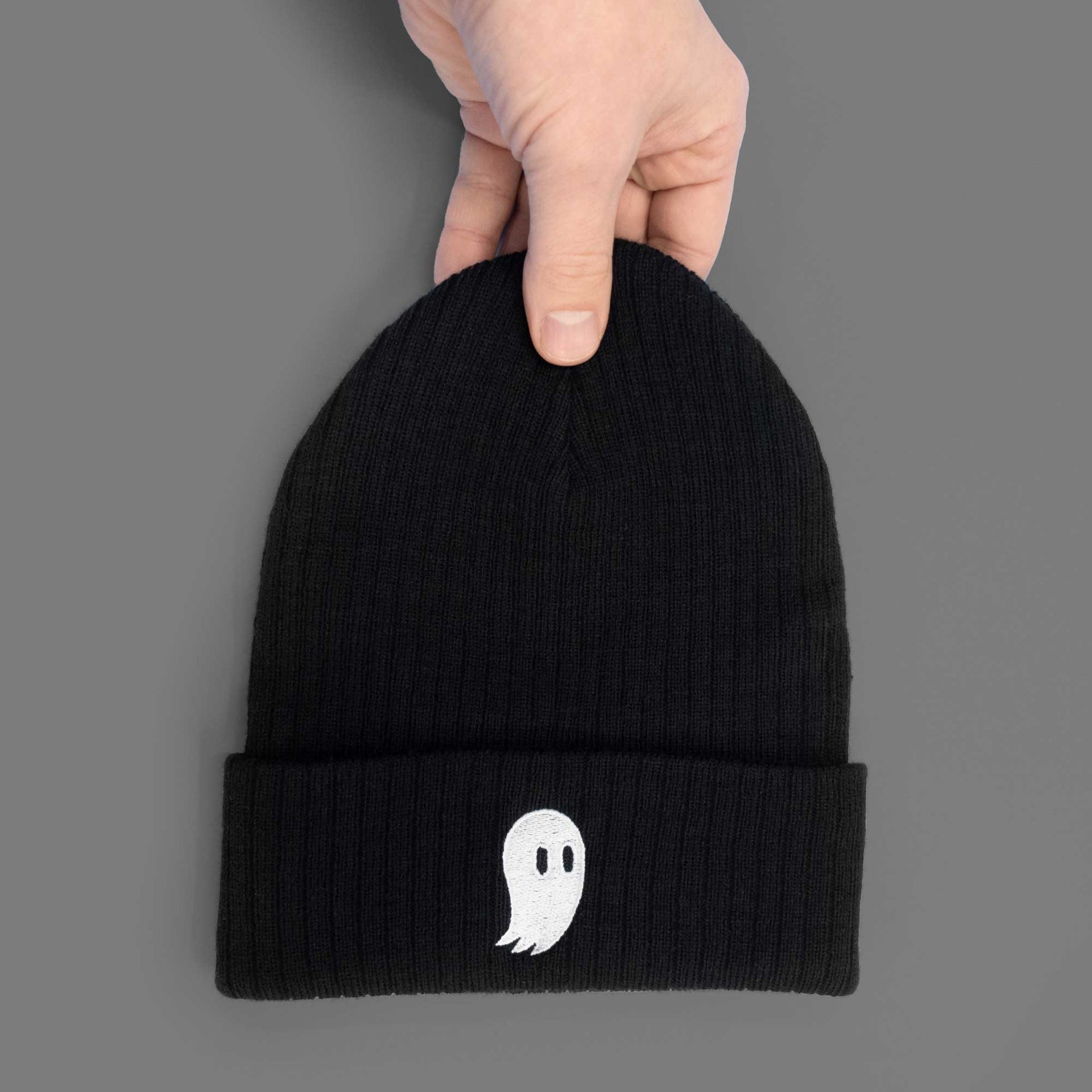 a white ghost embroidered on soft black beanie in hand