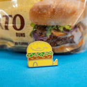 friendly burger enamel pin in front of burger bun package