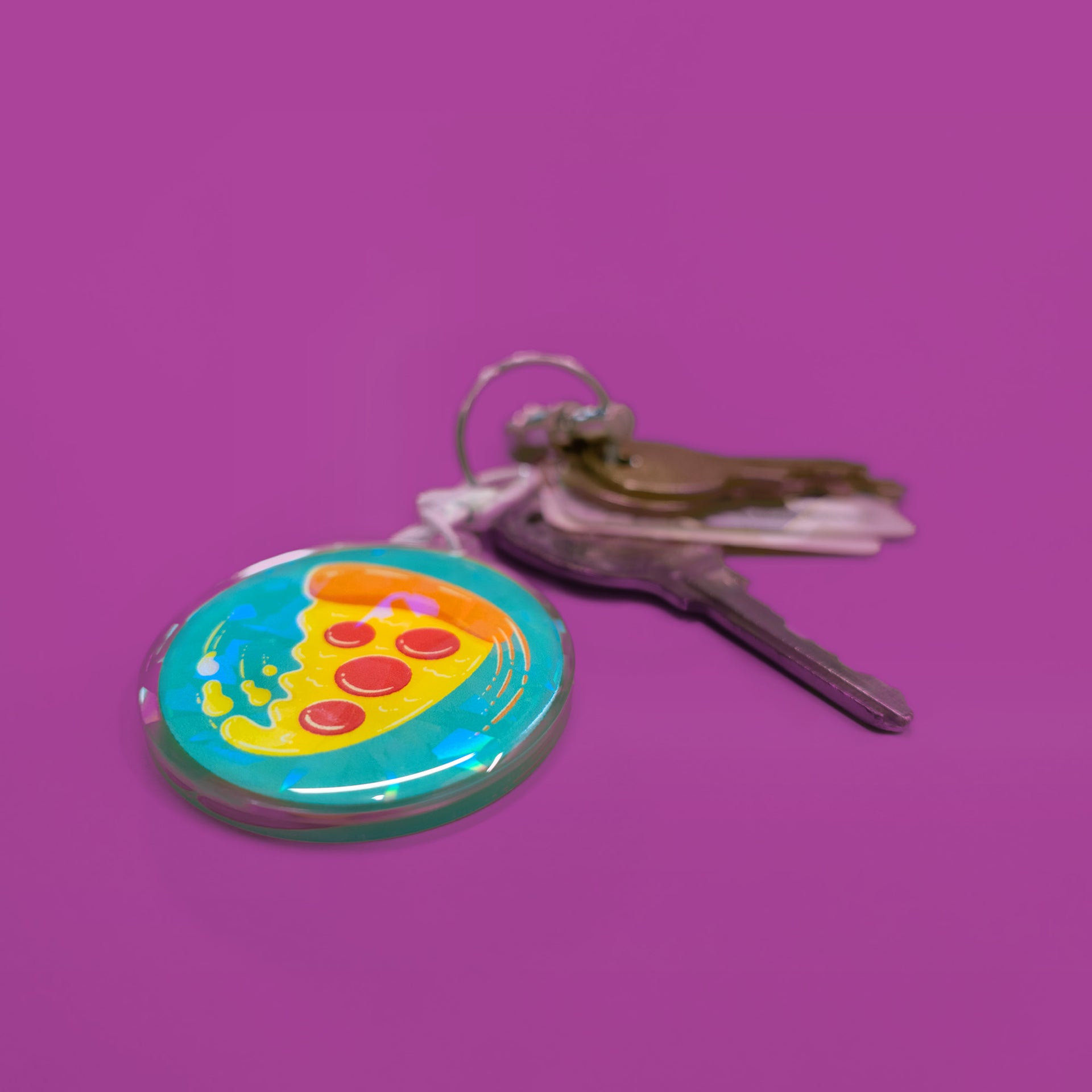 swirling pizza art on a circular holographic keychain with keys