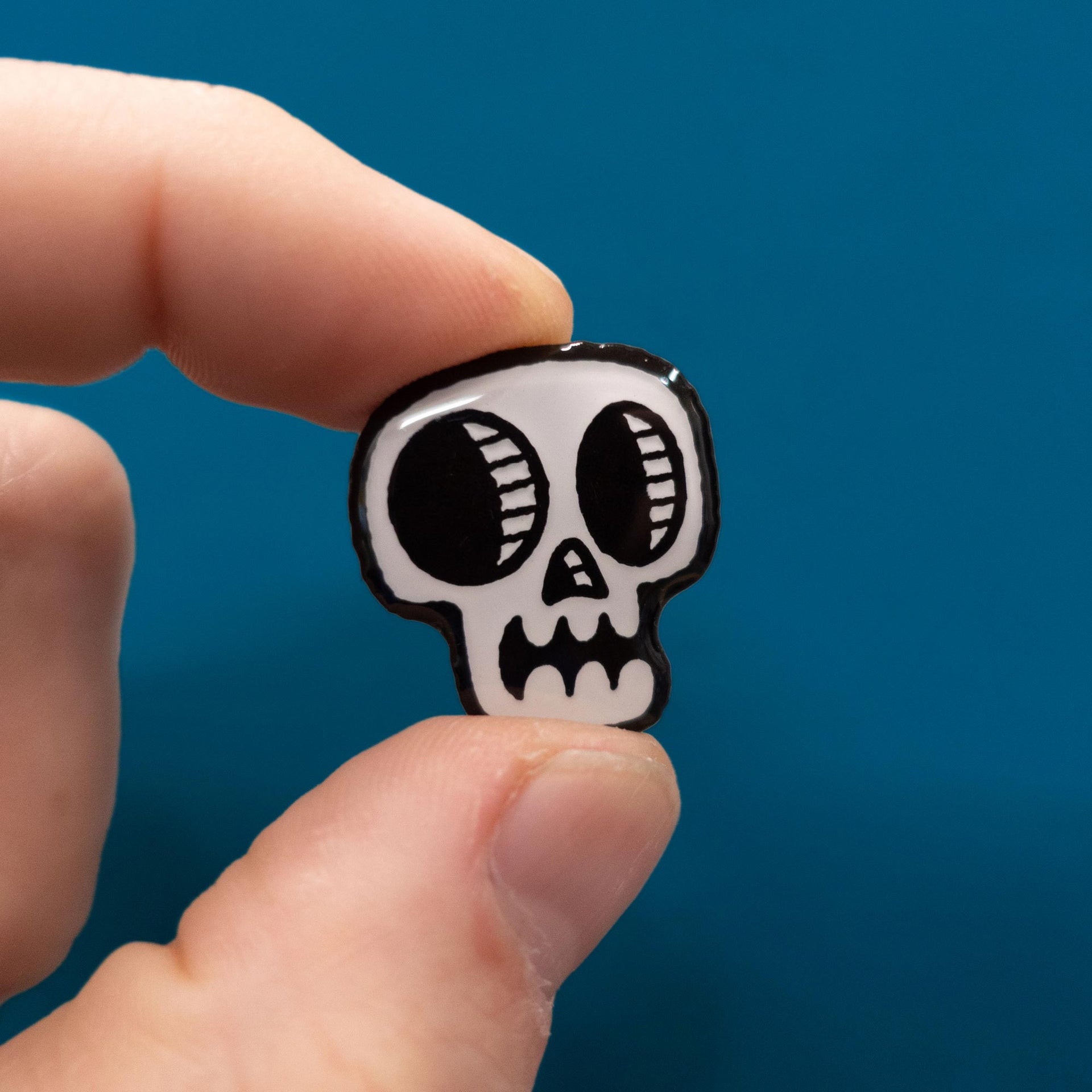 glow in the dark skull enamel pin in hand